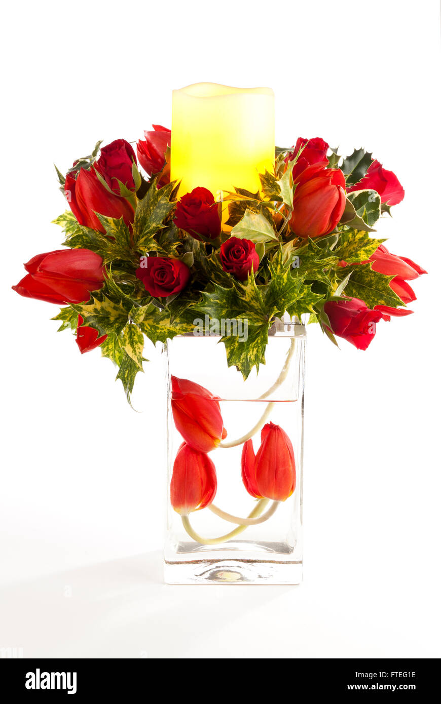 Ein Blumenarrangement mit roten Tulpen, Rosen, Osmanthus und einer beleuchteten Wachskerze Stockfoto