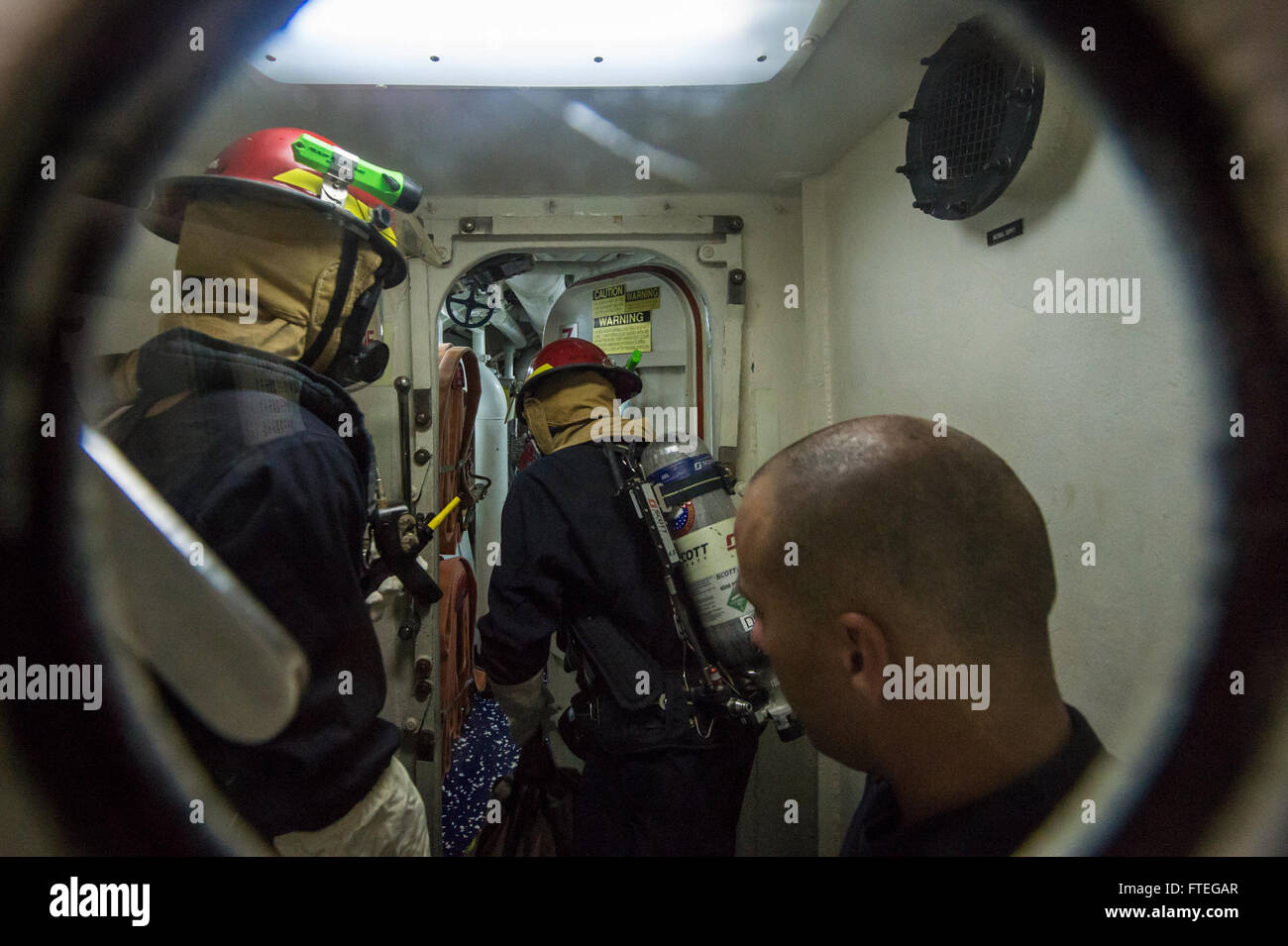 Seeleute an Bord der USS Cole verlassen einen luftverschlossenen Raum während einer Schadensuntersuchungsübung im Rahmen einer allgemeinen Viertelübung im Mittelmeer, um die Bereitschaft und Sicherheit zu gewährleisten. Stockfoto