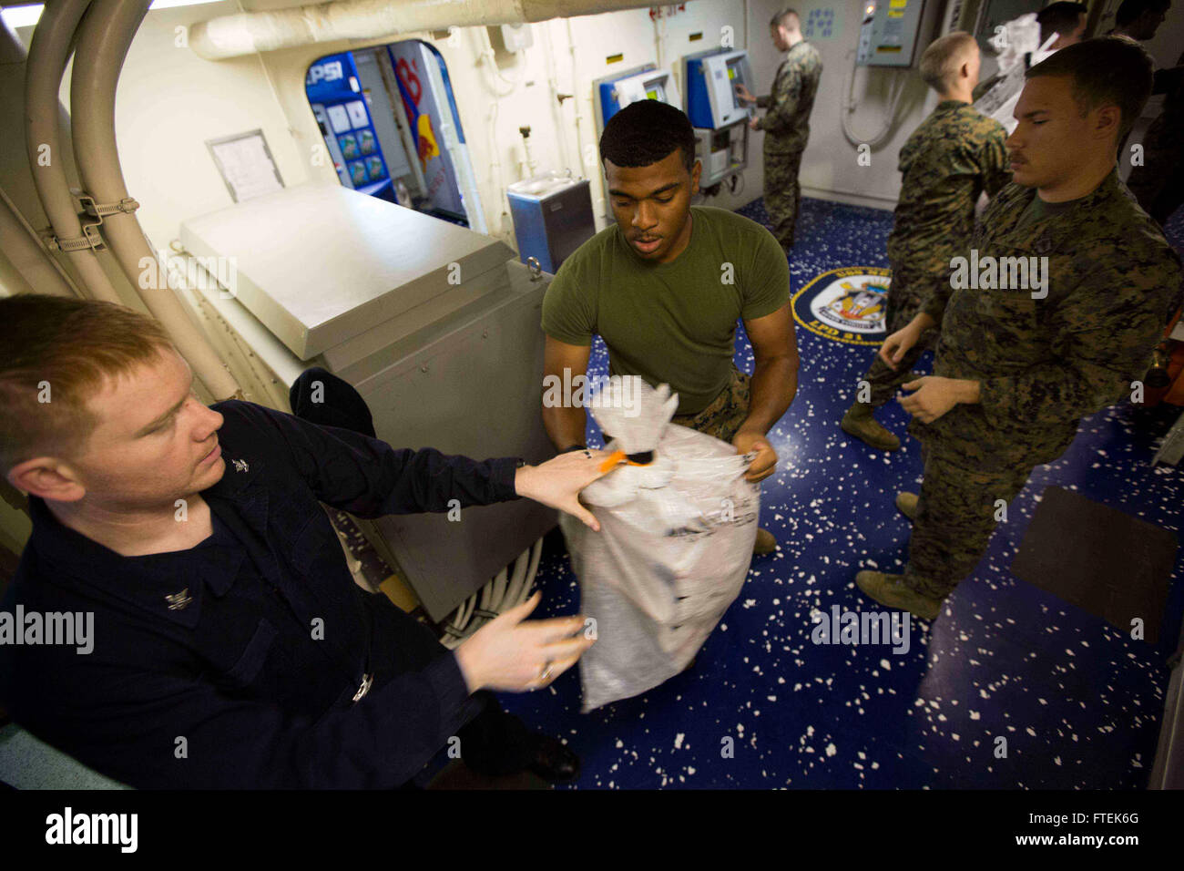 150109-M-YH418-005 Mittelmeer (9. Januar 2015) CPL Anthony Millender, ein Verkehrs-Management-Spezialist, Center, mit dem 24. Marine Expeditionary Unit (MEU), durchläuft eine Tasche von Mail während einer Auffüllung auf See an Bord der San-Antonio-Klasse amphibischen Dock Transportschiff USS New York (LPD-21) 9. Januar 2015. Durchführung der 24. MEU und Iwo Jima amphibisches bereit Gruppe Marinebetriebe in den USA 6. Flotte Bereich der Maßnahmen zur Erhöhung der Sicherheit der Vereinigten Staaten in Europa interessiert. (Foto: U.S. Marine Corps CPL. Todd F. Michalek/freigegeben) Stockfoto