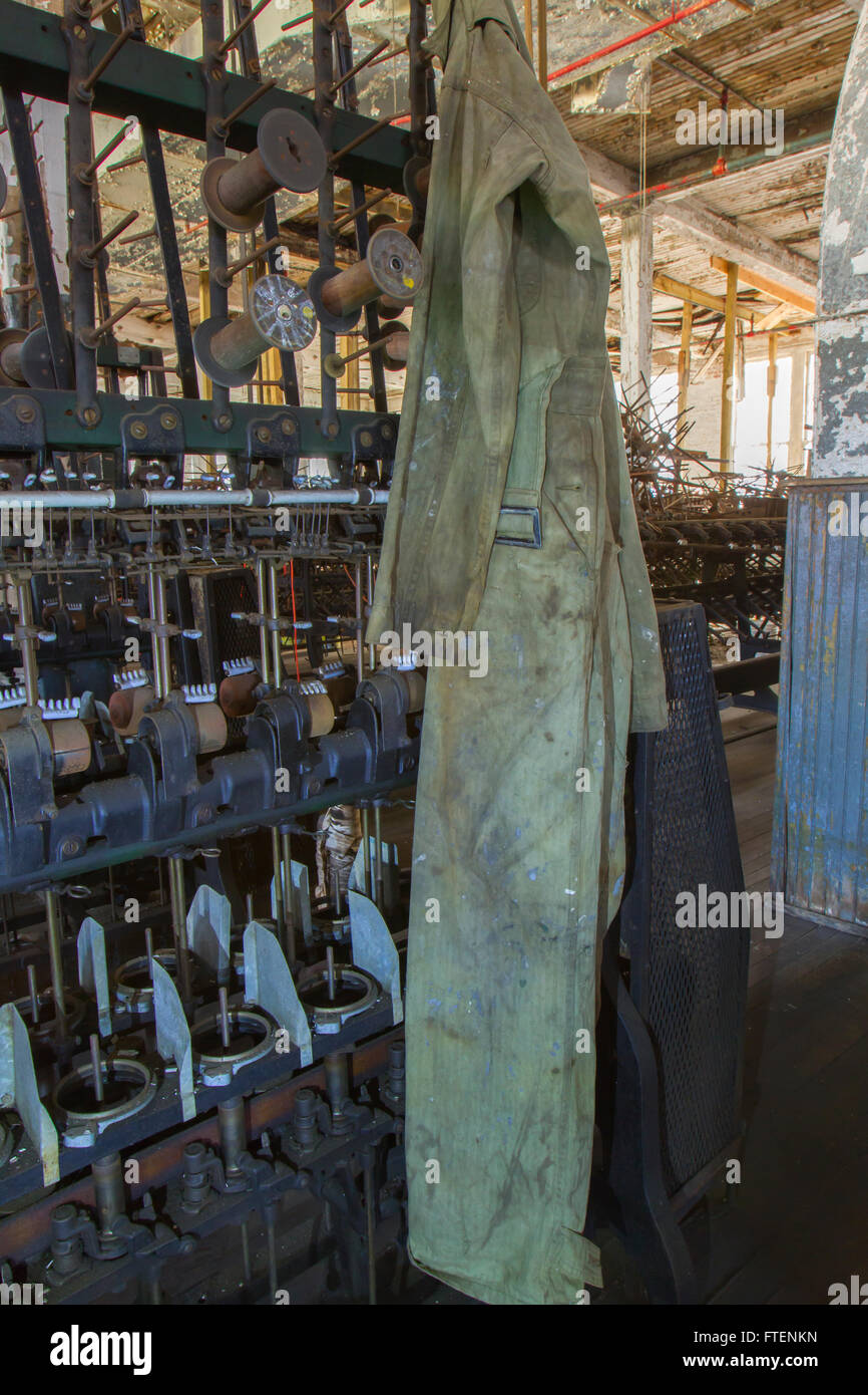 Schutzanzüge hängt an Maschinen in Fabrikhalle der Wende des Jahrhunderts Seide Fabrik zu werfen. Stockfoto