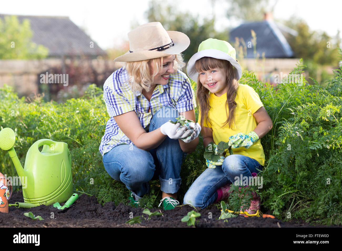 Kind Mädchen mit Mutter glücklich pflückt Erdbeeren auf Erdbeereflecken Stockfoto