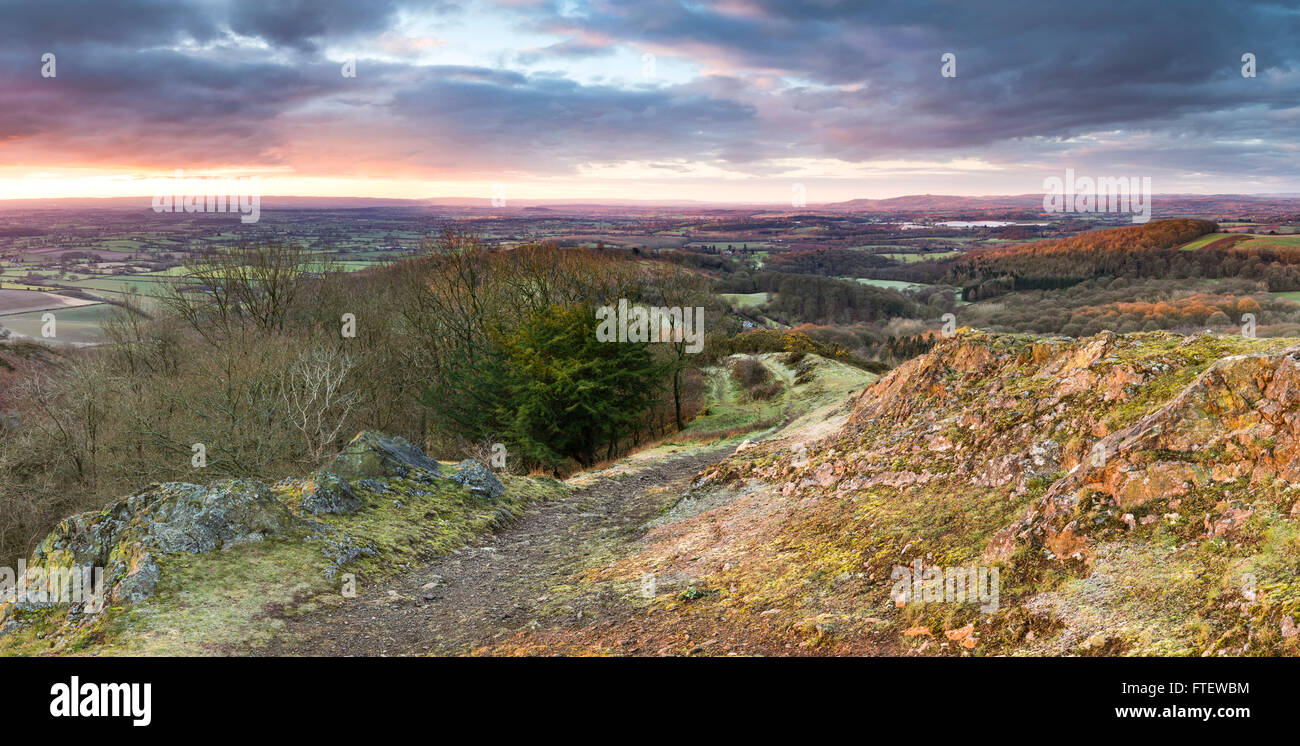 Sunrise leuchtet auf den Fußweg und Felsen über Raggedstone Hügel auf die Malvern Hills, Herefordshire an einem kalten frostigen Morgen. Stockfoto