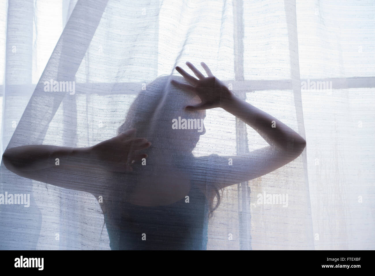 Geheimnisvolle Frauengestalt hinter die Vorhänge am Fenster Stockfoto