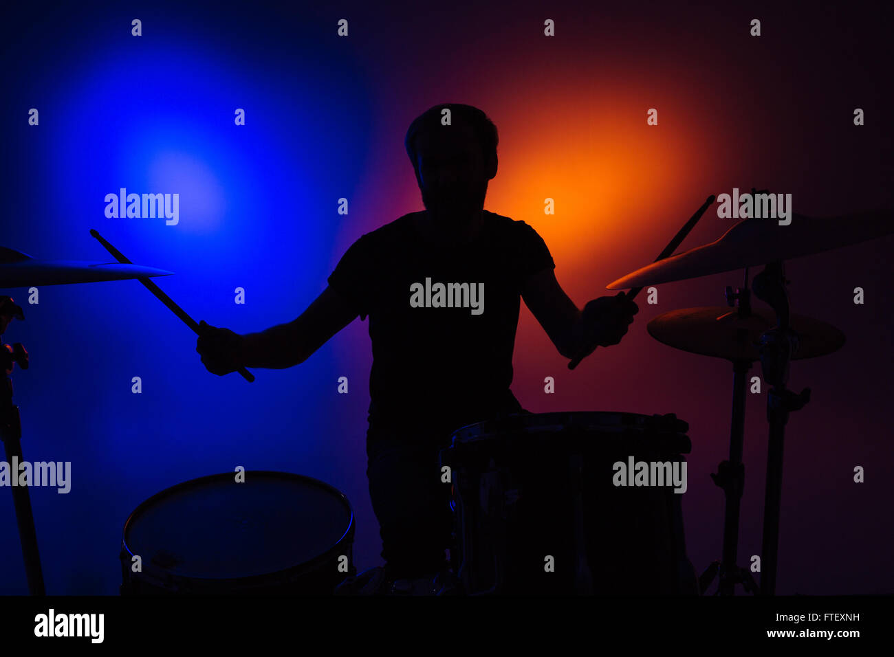 Silhouette der Mann Schlagzeuger sitzen und Schlagzeug mit Stöcken über bunte backgound Stockfoto