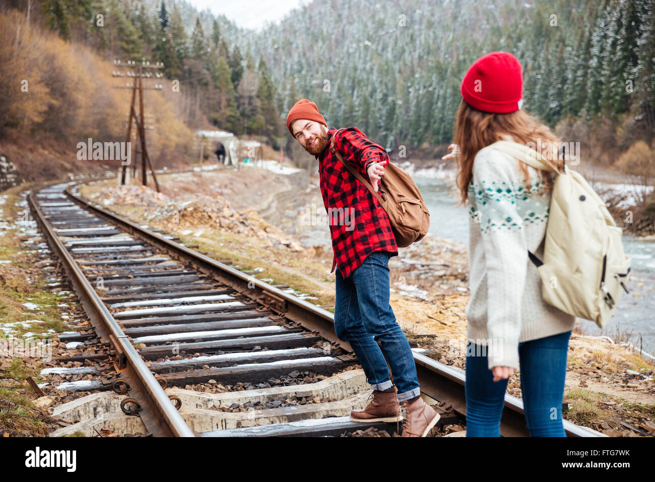 Schöne junge Paar erreichen Hände und wachen auf Eisenbahn in Bergen Stockfoto