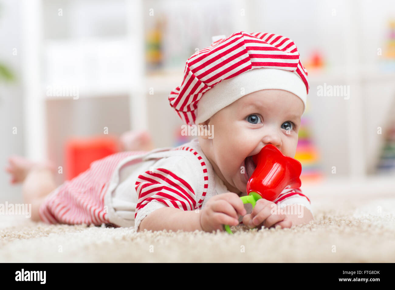 Baby Spielzeug halten und liegend auf Bauch im Kinderzimmer Stockfoto