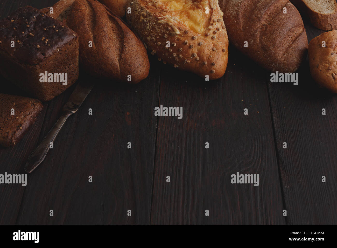 Verschiedenen Vollkorn Brot auf poliertem Holztisch. Erhöhten Blick Stil hell-dunkel Stockfoto