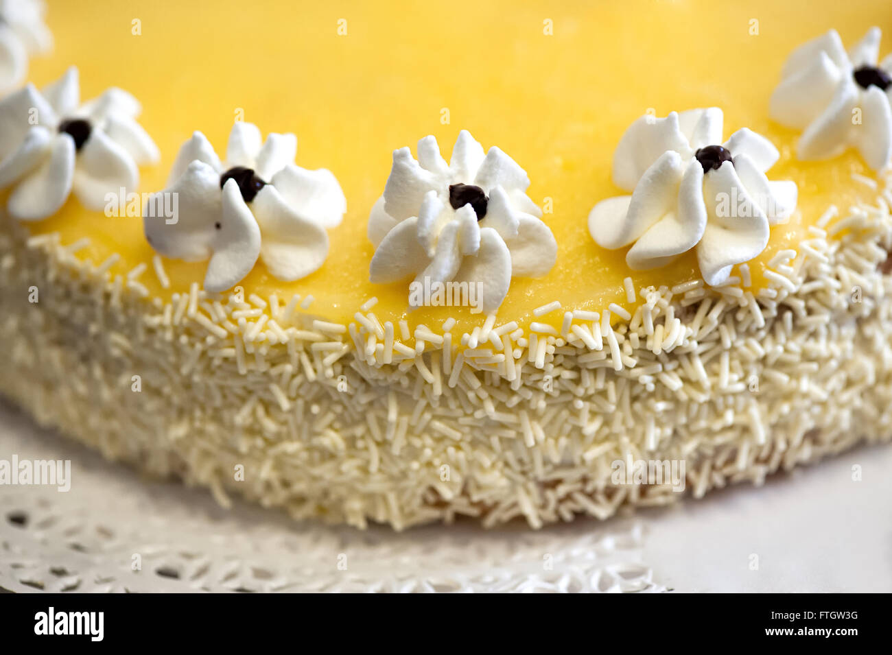 Hohen Winkel schließen sich kulinarische Stillleben mit hausgemachte Zitronenkuchen mit Zuckerguss Blumen geschmückt und Kokosnuss Streusel- Stockfoto