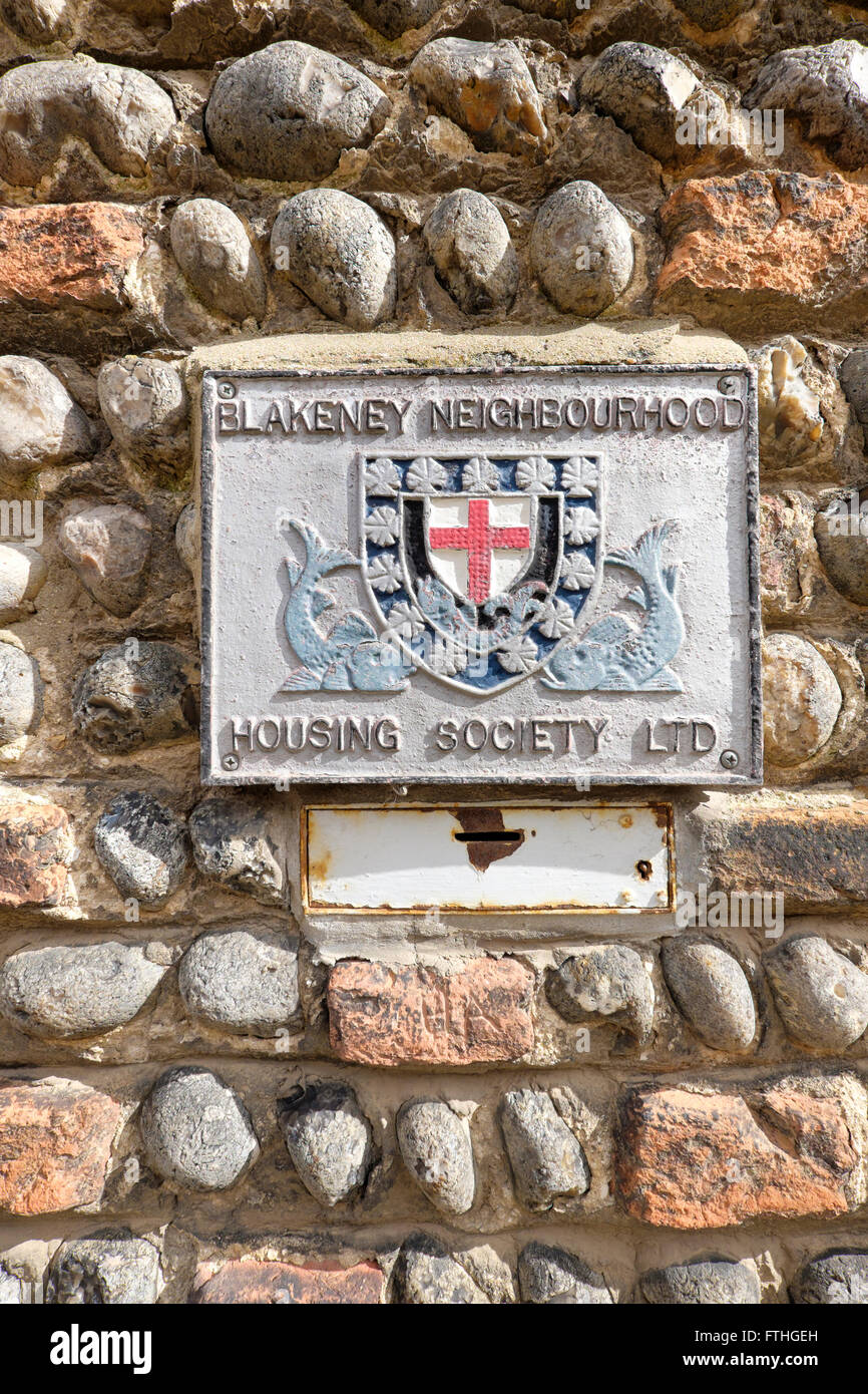 Zeichen und Spende Box für Blakeney Nachbarschaft Housing Society Ltd auf den Feuerstein Steinmauer eines Hauses Stockfoto