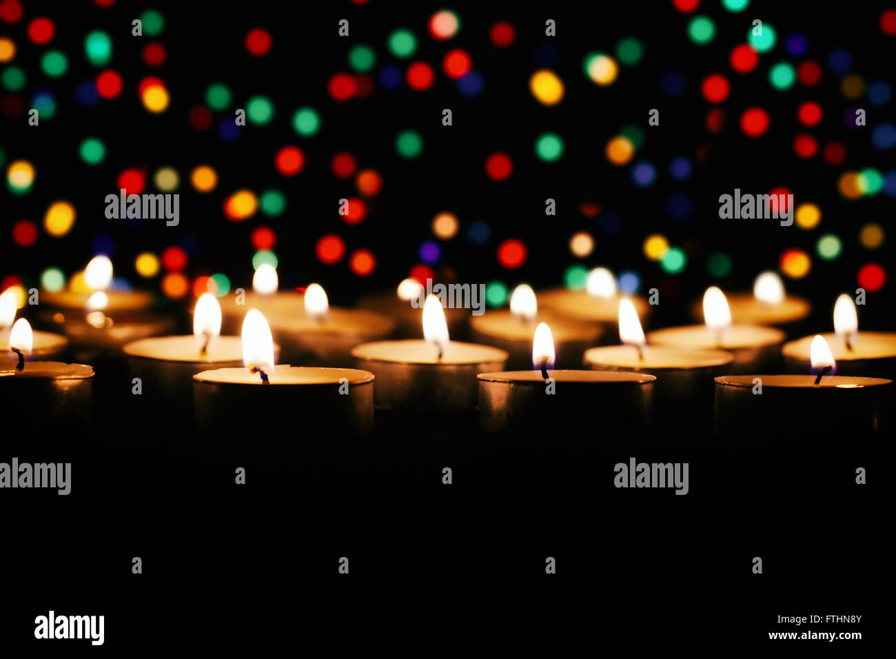 Brennende Kerze vor dem Hintergrund der bunten Lichtern Stockfoto