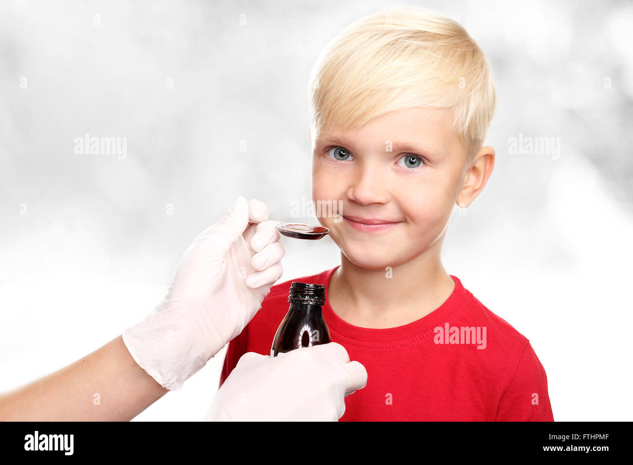 Ein Kind mit einem Arzt, ein Heilmittel gegen die Grippe. Einen köstlichen Sirup, der junge trinken ein Heilmittel gegen Erkältungen. Stockfoto