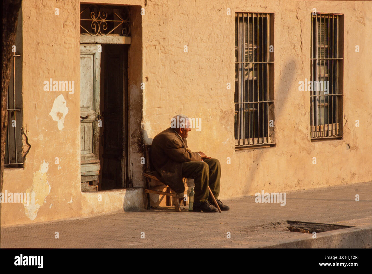 Ein Alter Mann sitzt Outide sein Haus in der Sonne, Velora Stockfoto
