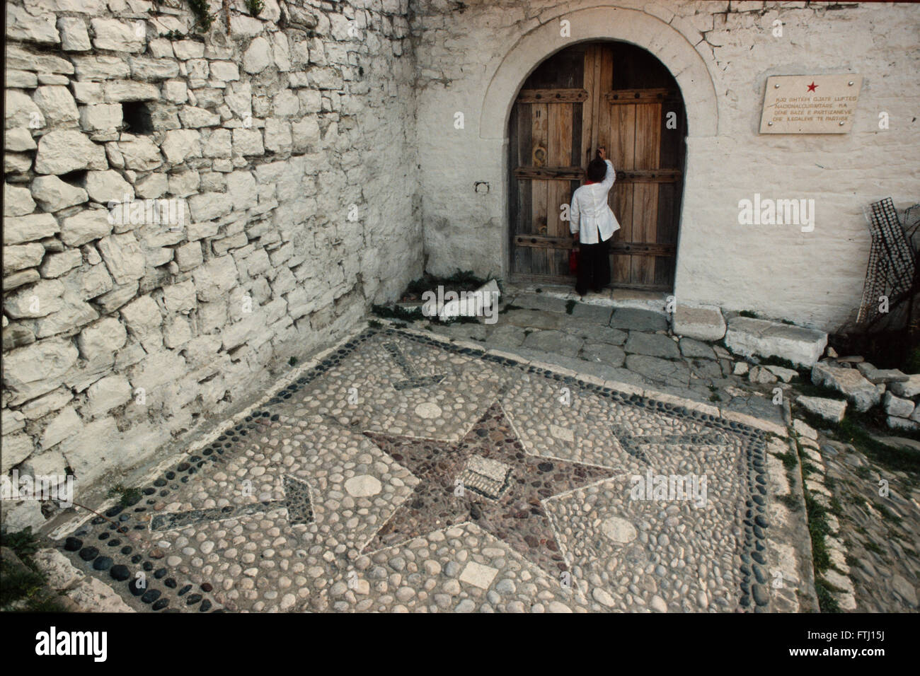 Ein Junge klopfen an einer Tür eines Hauses, das von den Partisanen während des 2. Weltkrieges, Berat, Albanien verwendet wurde. Stockfoto