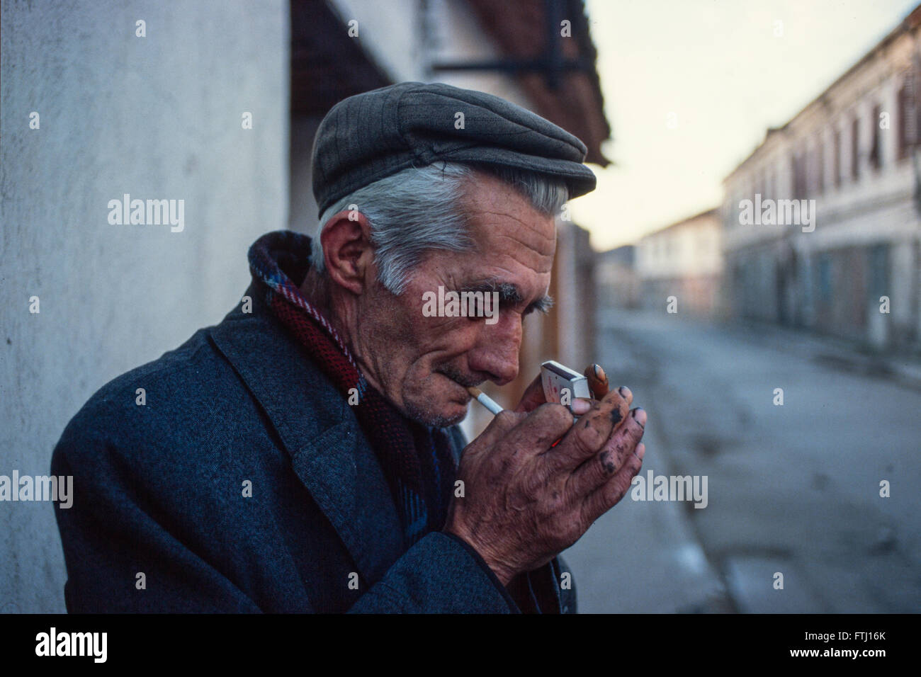 Ein Alter Mann zündet sich seine Zigarette auf der Straße, Shkoder, Albanien. Stockfoto