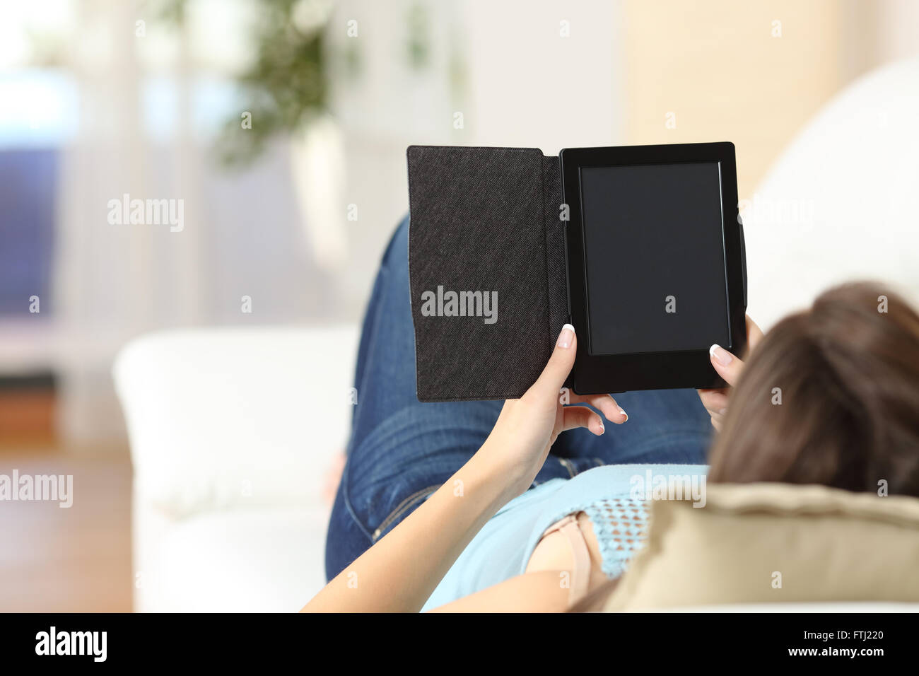 Mädchen, ein Ebook zu lesen und zeigt schwarzen Bildschirm auf einer Couch zu Hause Stockfoto