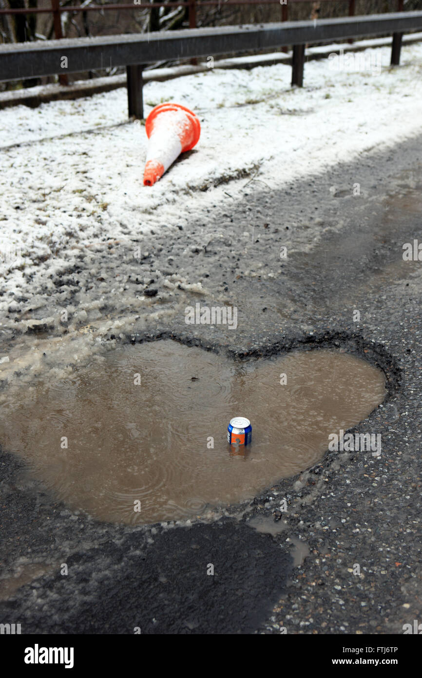 Großen Schlagloch auf einer schottischen Straße (A82) mit einem kohlensäurehaltige Getränke können zeigt die Tiefe der Bohrung Stockfoto