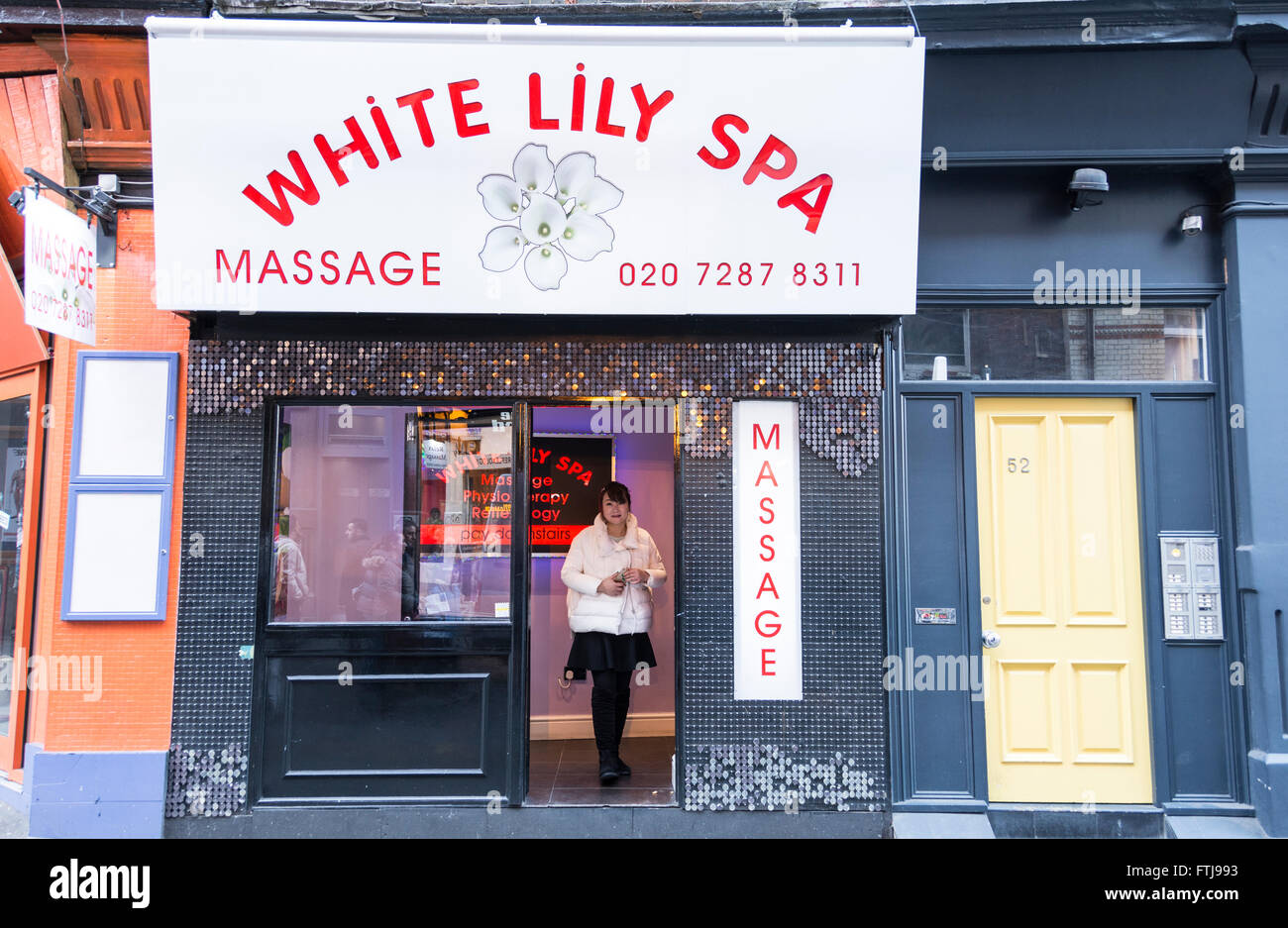 Die Frau winkt für Unternehmen aus der Eingang von einem Massagesalon in Londons SOHO-Bereich Stockfoto