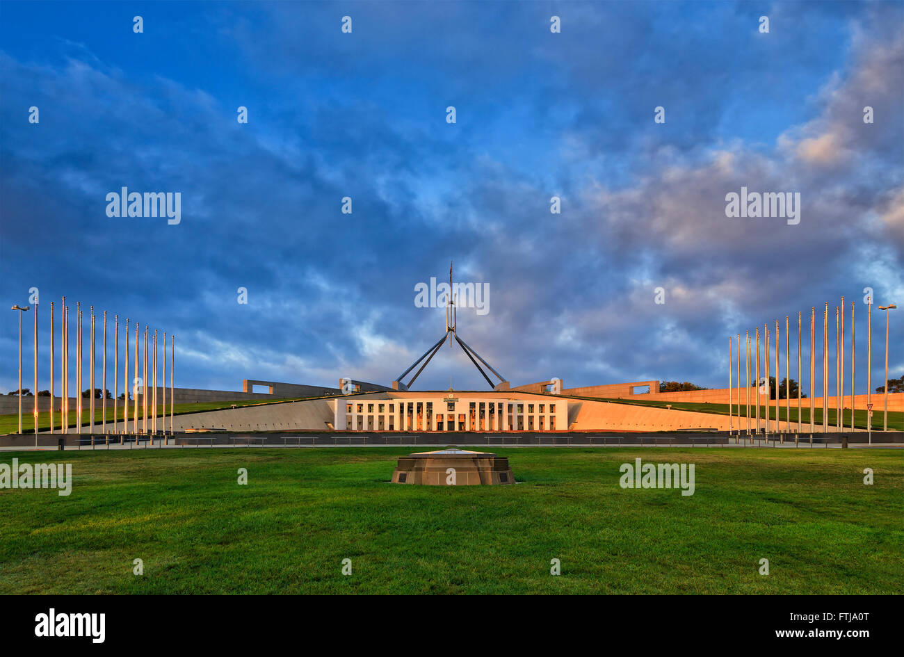 grüner Rasen und hohen Fahnenmasten mit Fahnen vor neuen Parliament House in Canberra bei Sonnenaufgang. Australian Capital territory Stockfoto