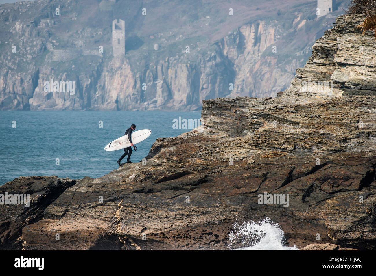 Ein Surfer klettert Felsen an Porthleven in Cornwall. Stockfoto