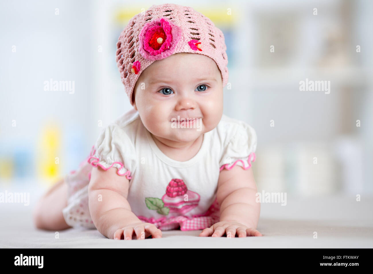 lächelndes Babymädchen liegend auf dem Bauch im Kinderzimmer Stockfoto