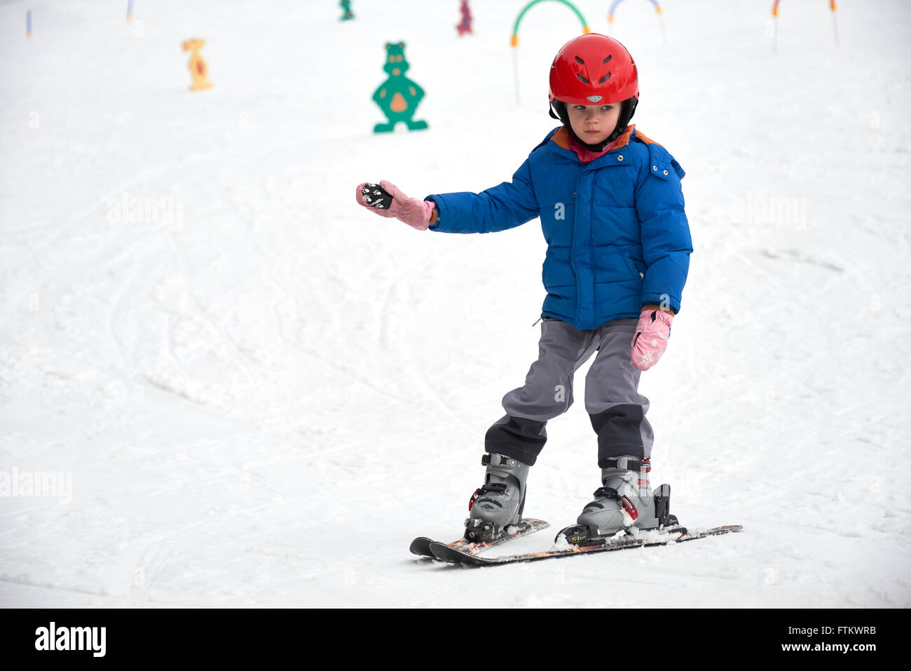 Kind beim Skifahren in den Bergen. Mädchen mit Schutzhelm Skifahren lernen in der Schule. Wintersport für Familien mit kleinen Kindern. Stockfoto