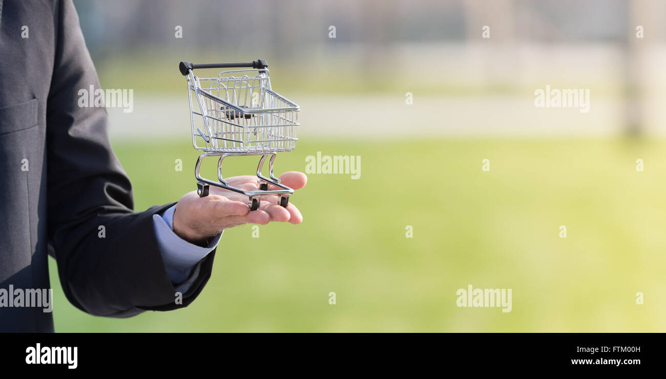 Geschäftsmann hält einen Einkaufswagen, Konsumismus Hintergrund Fotografie Stockfoto