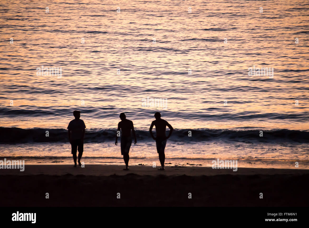 Silhouetten von Menschen zu Fuß am Strand bei Sonnenuntergang Stockfoto
