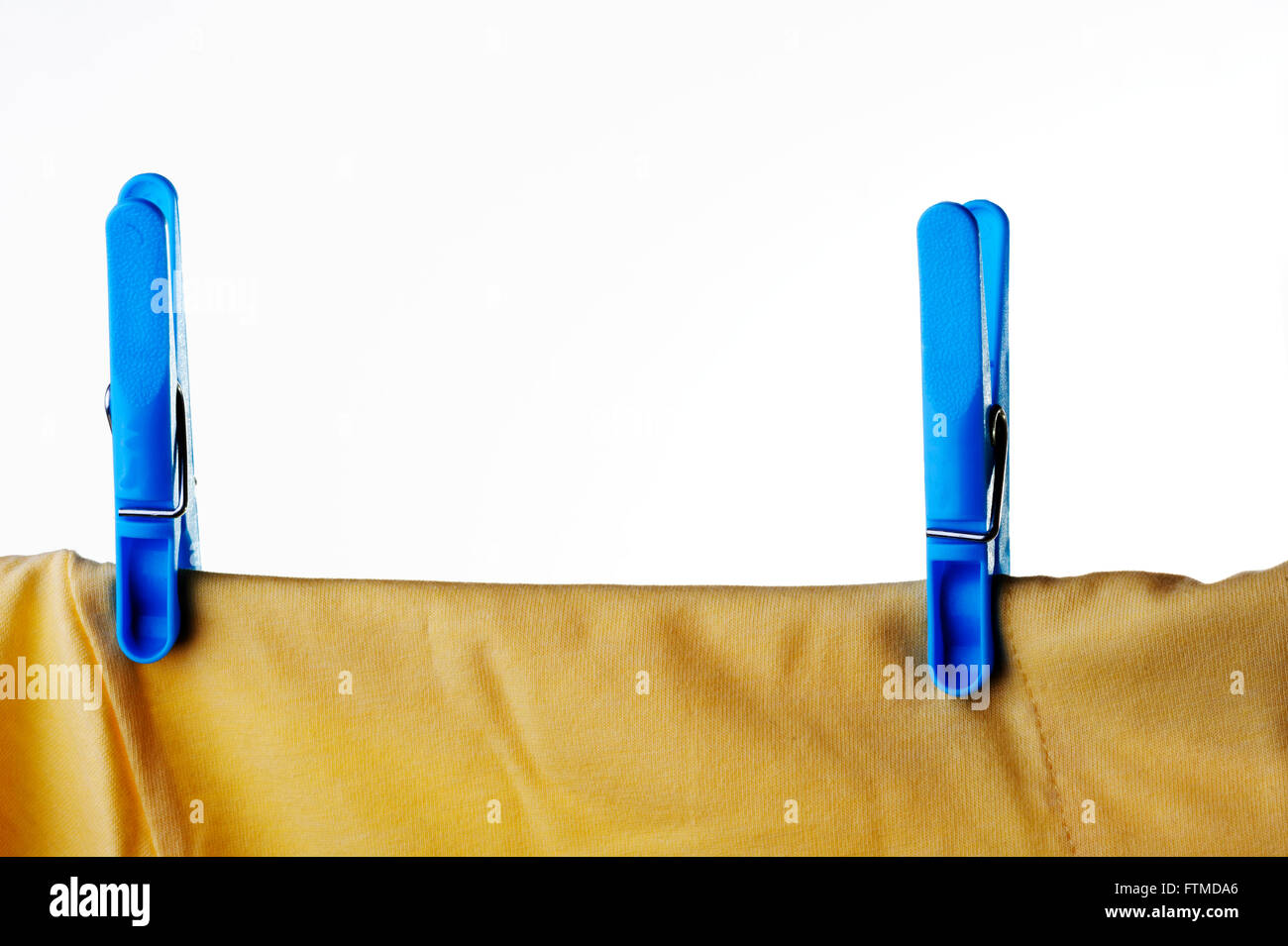 Blaue Kunststoff Wäscheklammer oder Pin ein gelbes T-shirt auf Wäscheleine zu sichern. Stockfoto