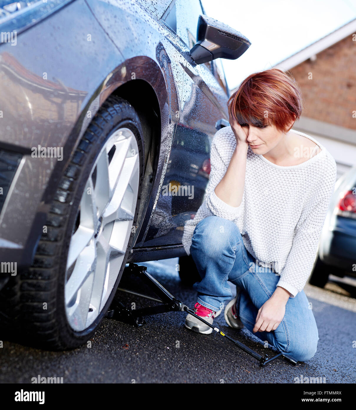 Frau Radwechsel auf ihrem Auto Stockfoto