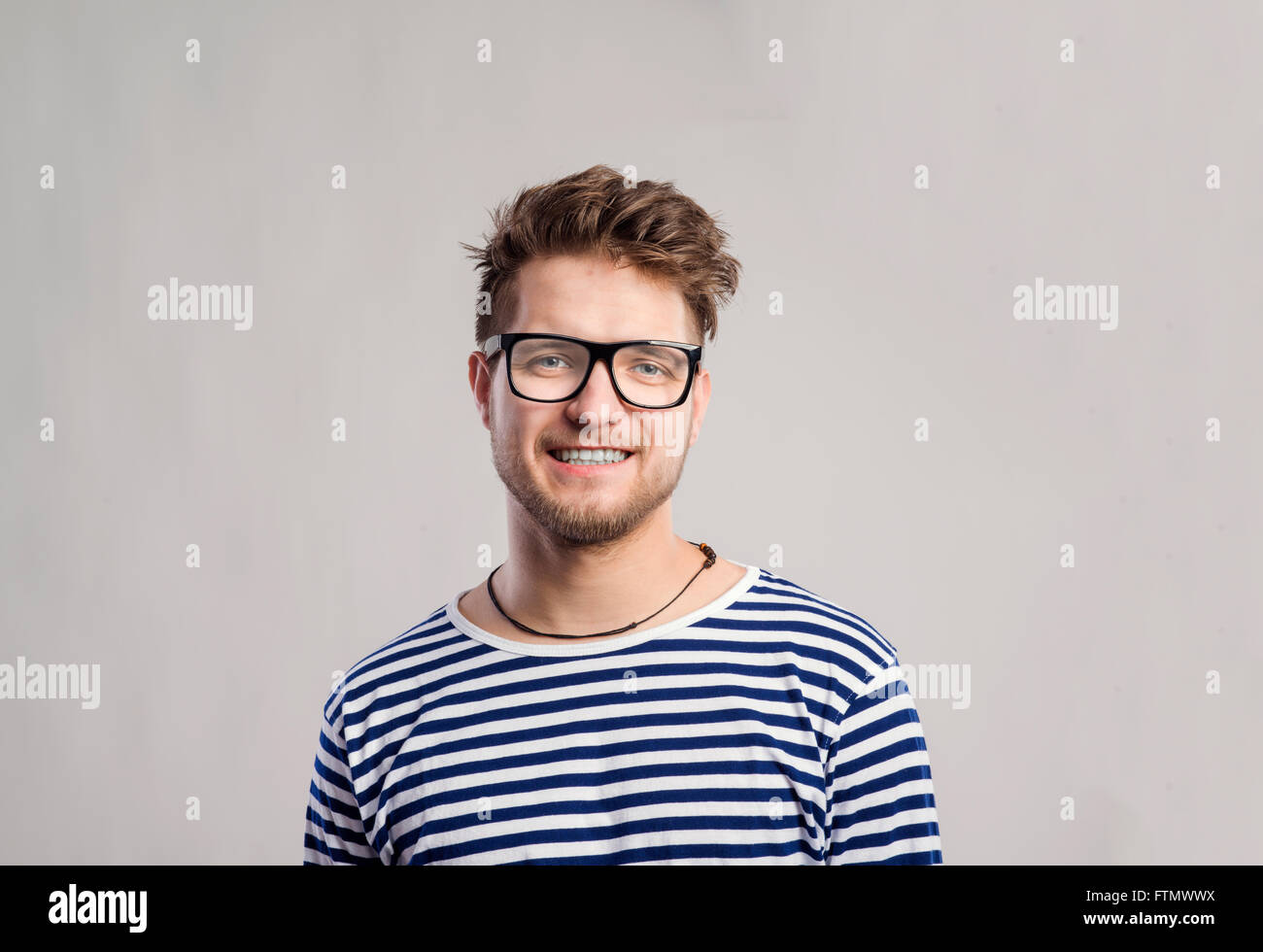 Mann im gestreiften T-shirt und Brillen vor grauem Hintergrund. Stockfoto