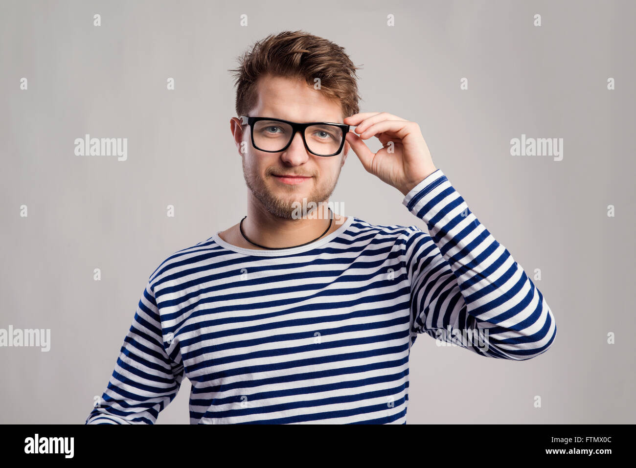 Mann im gestreiften T-shirt und Brillen vor grauem Hintergrund. Stockfoto