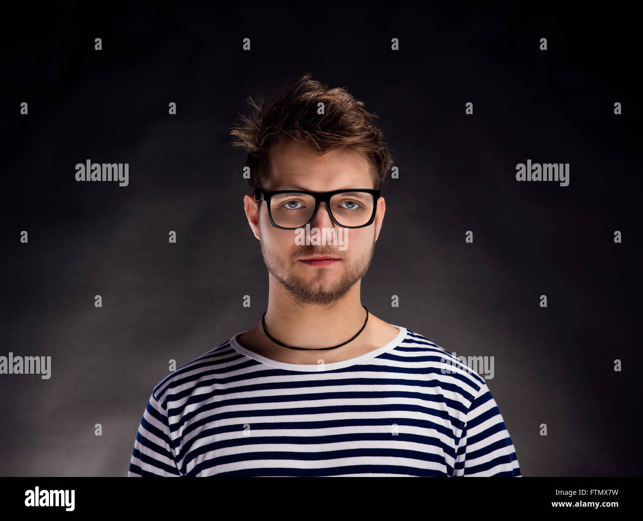 Mann im gestreiften T-shirt und Brillen vor schwarzem Hintergrund. Stockfoto