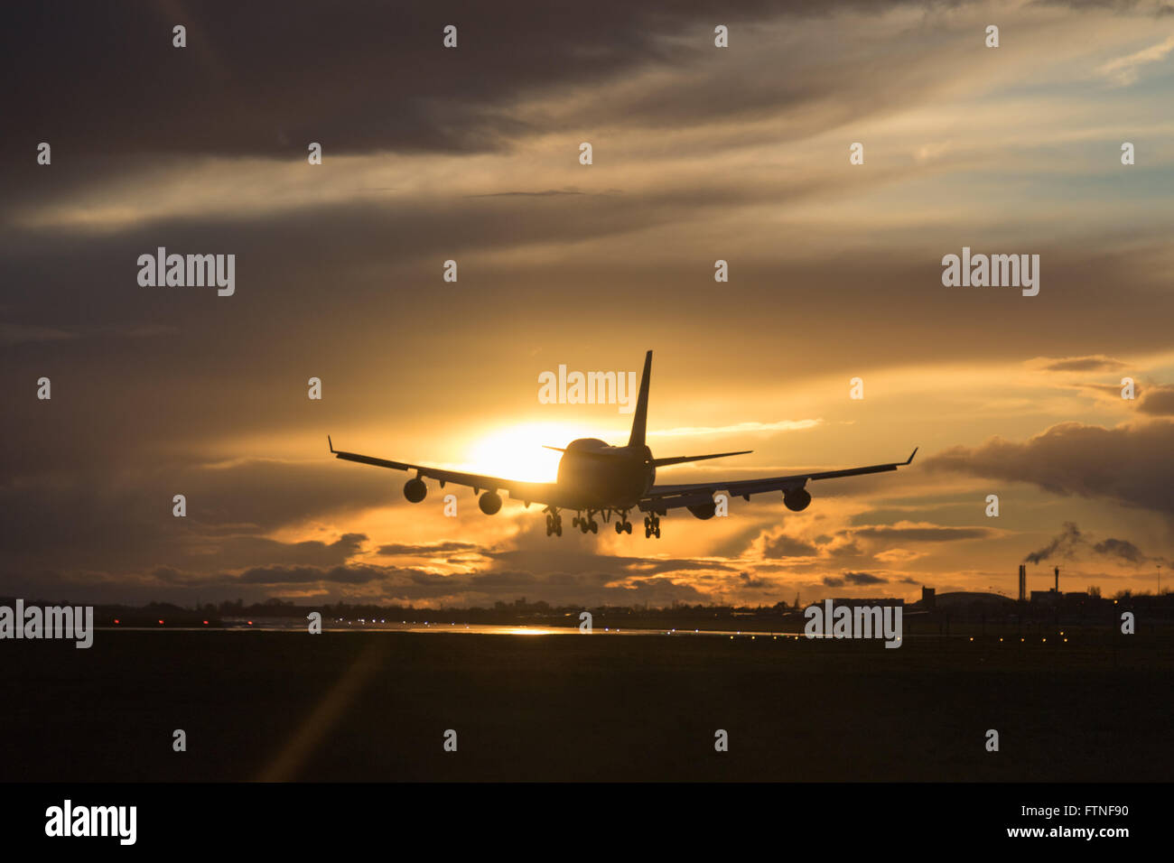 Eine British Airways Boeing 747-400 landet am Flughafen London Heathrow als der Sonnenuntergang beleuchtet die Wolken. Stockfoto