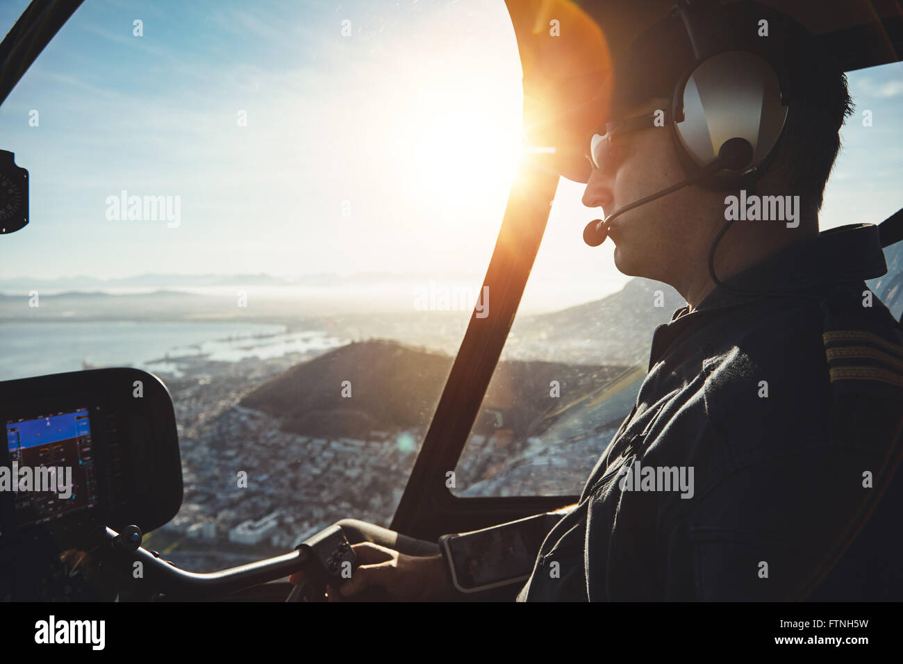 Nahaufnahme eines männlichen Piloten fliegen eines Hubschraubers über Kapstadt an sonnigen Tag Stockfoto