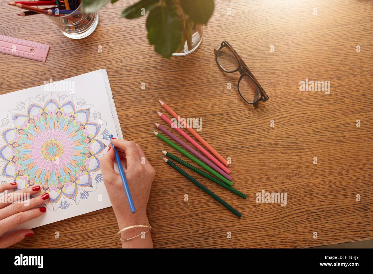 Schließen Sie herauf Bild der weiblichen Hände zeichnen in Erwachsene Malbuch auf einem Tisch zu Hause. Stockfoto