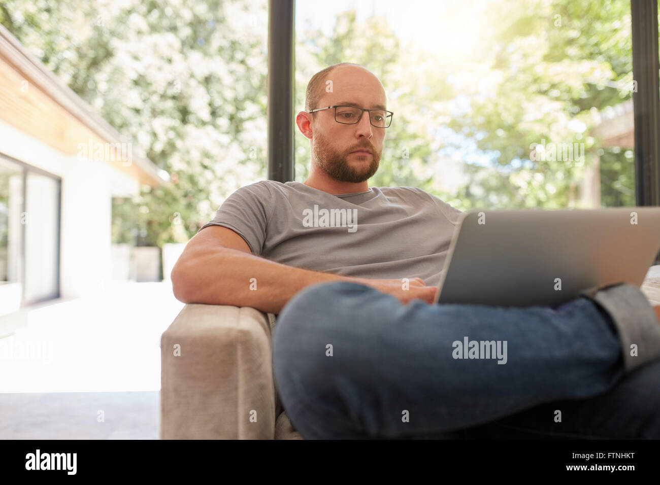 Porträt von reifer kaukasischen Mann auf dem Sofa sitzen und arbeiten am Laptop. Mann Internetsurfen auf Laptop-Computer. Stockfoto
