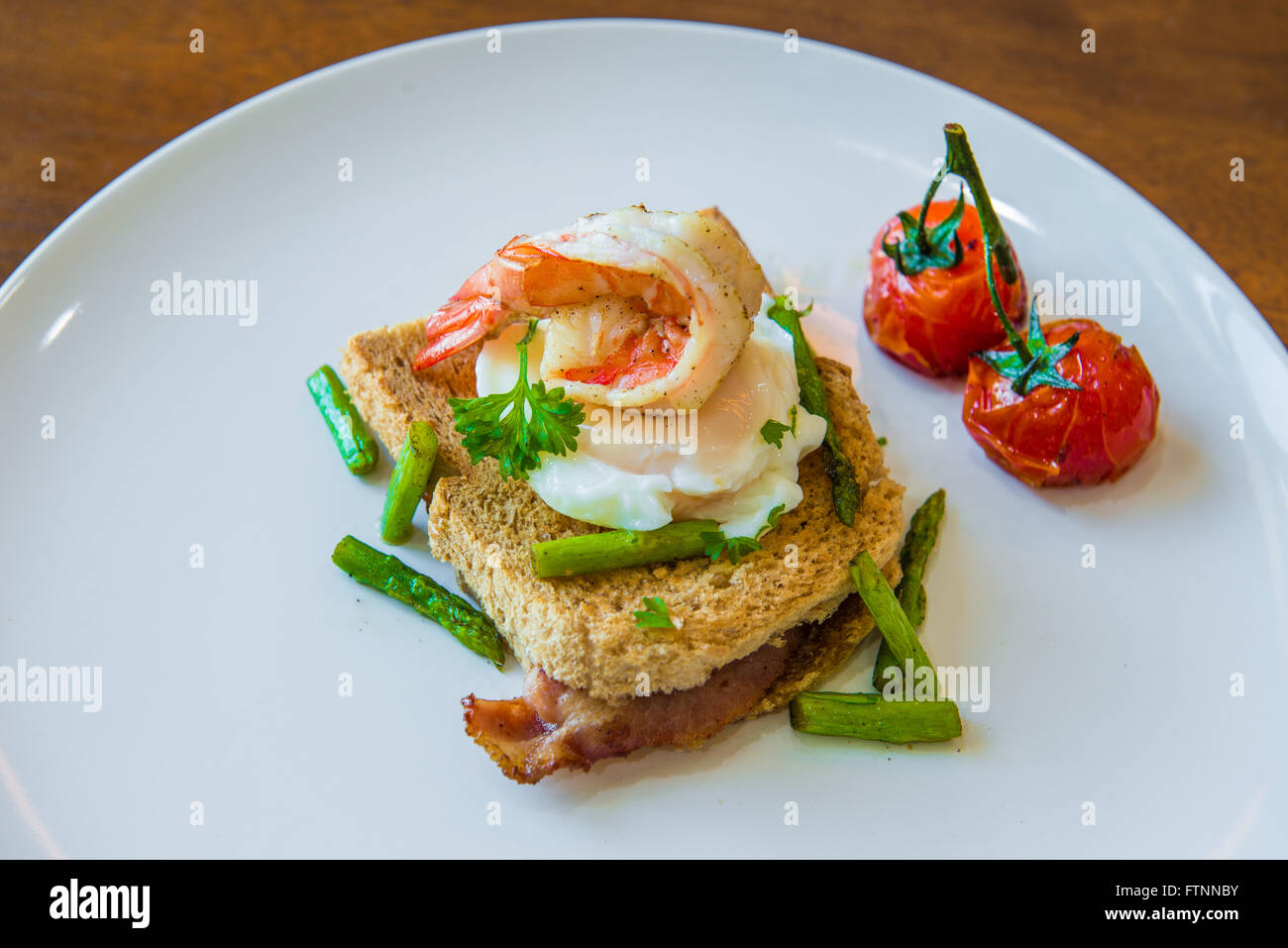 Sandwich mit pochiertem Ei, Parmaschinken und Tomaten Stockfoto