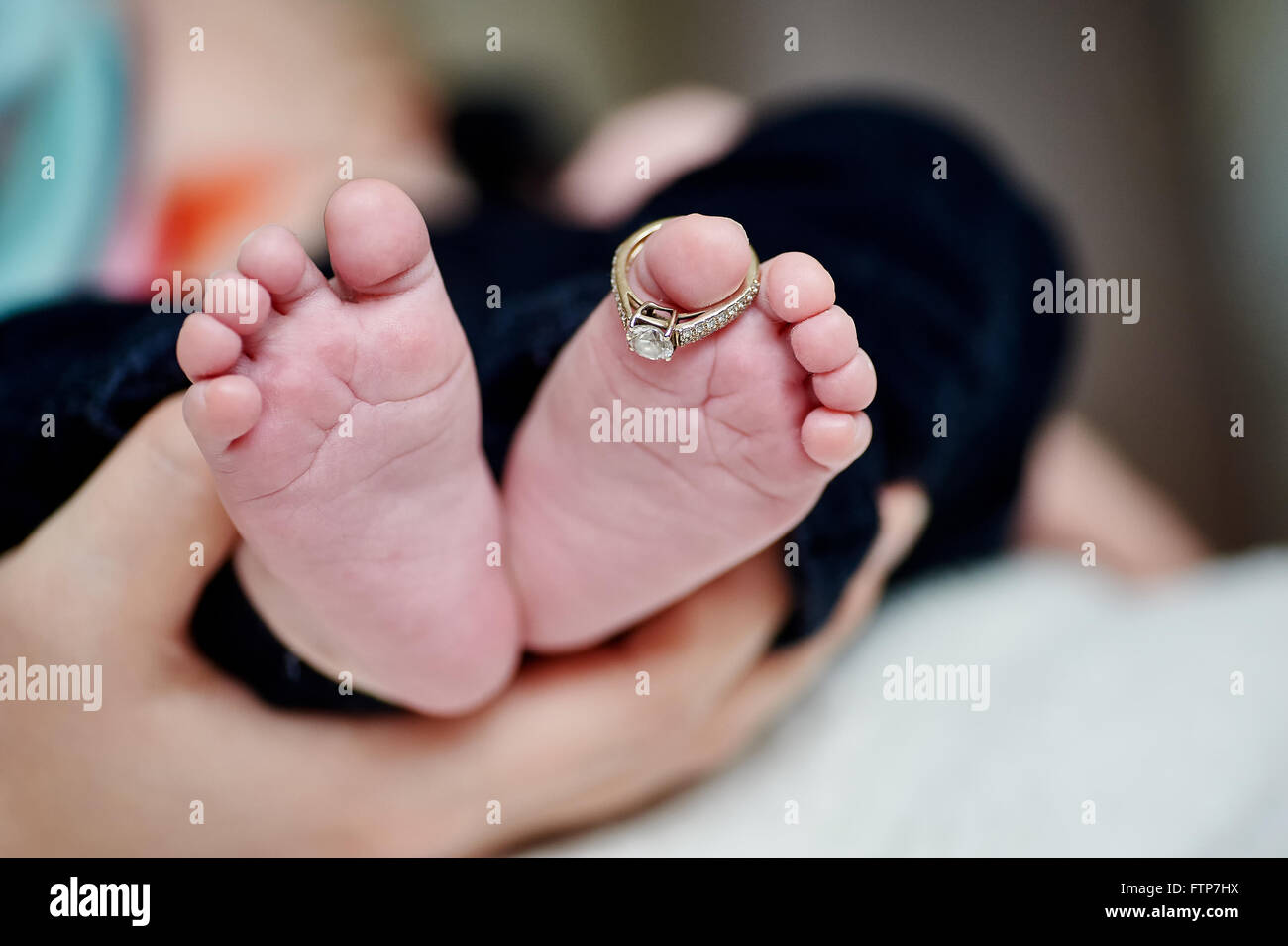 Neugeborenen ist Fuß in die Hand der Mutter mit Hochzeit Ringe am finger Stockfoto