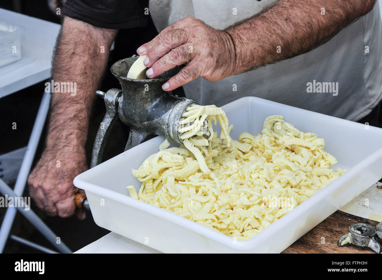 Einzelne Freiwillige Schleifen Mozzarella-Käse auf erste Partei Manioka Stockfoto