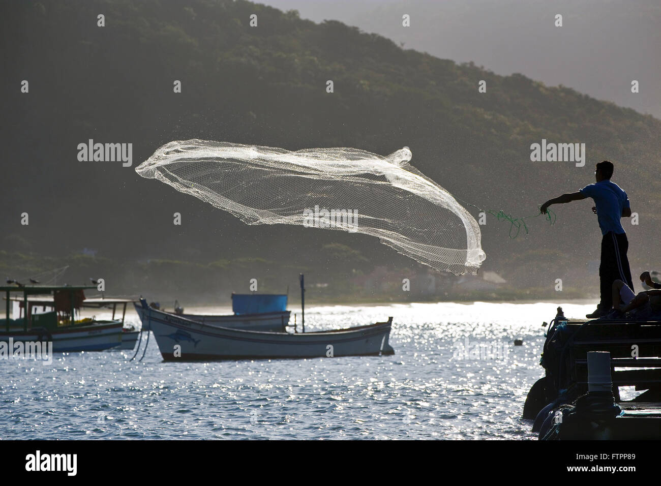 Fischer wirft sein Netz in den Gewässern der Strand Armacao - südlich von der Insel Stockfoto