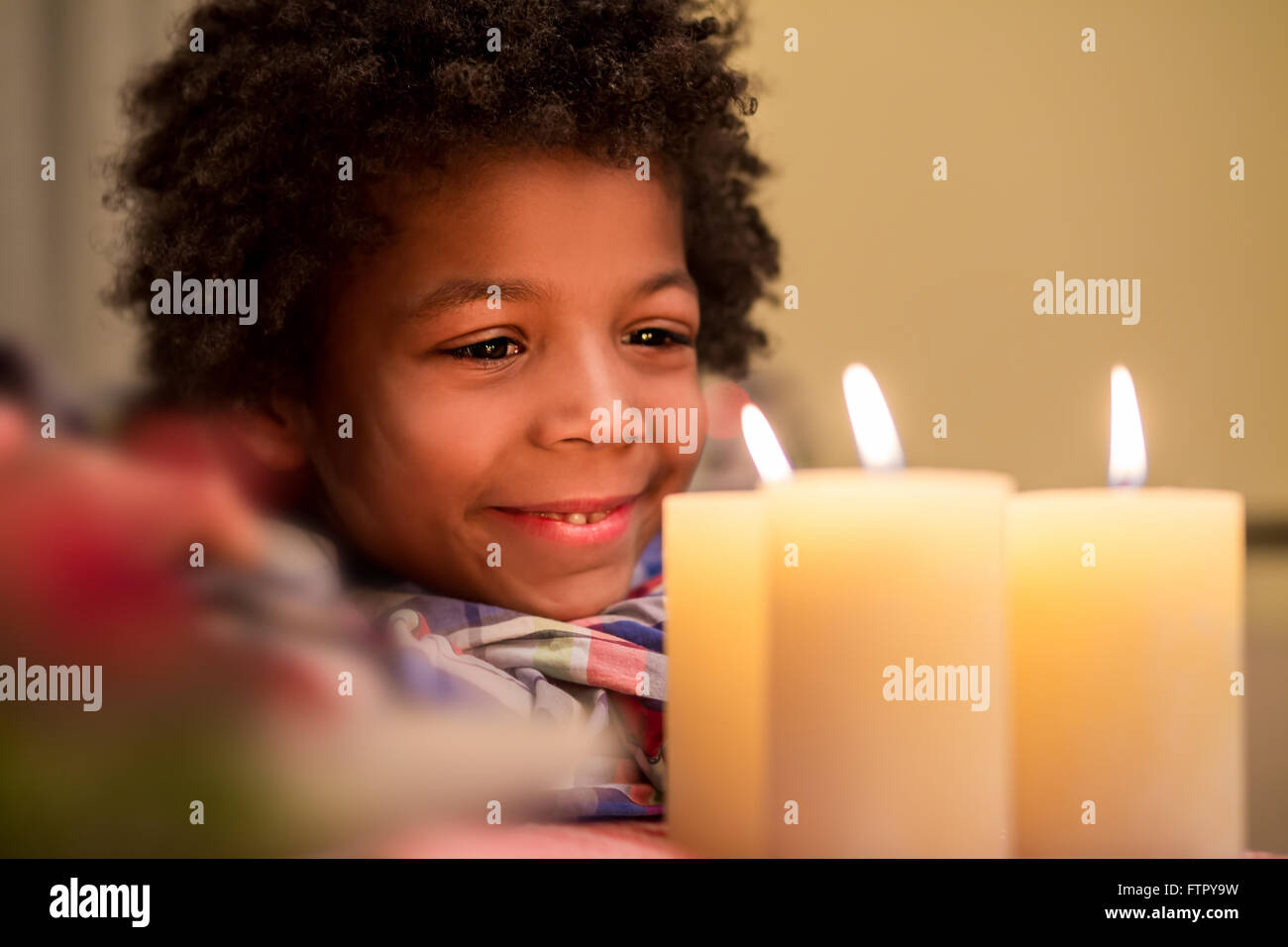 Glückliches Kind neben Weihnachtskerze. Stockfoto