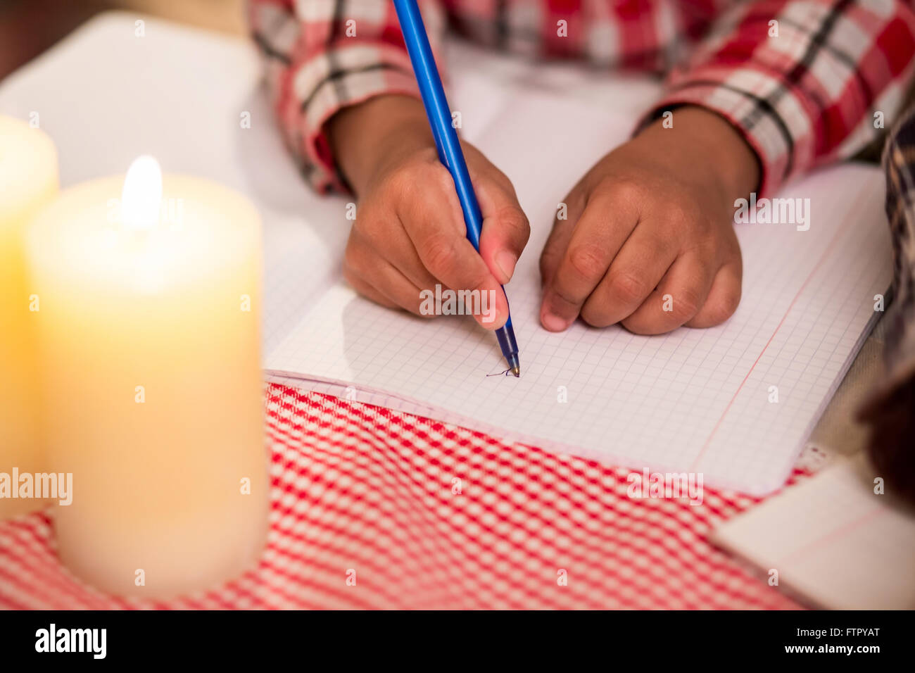 Kind schreibt einen Brief bei Kerzenschein. Stockfoto