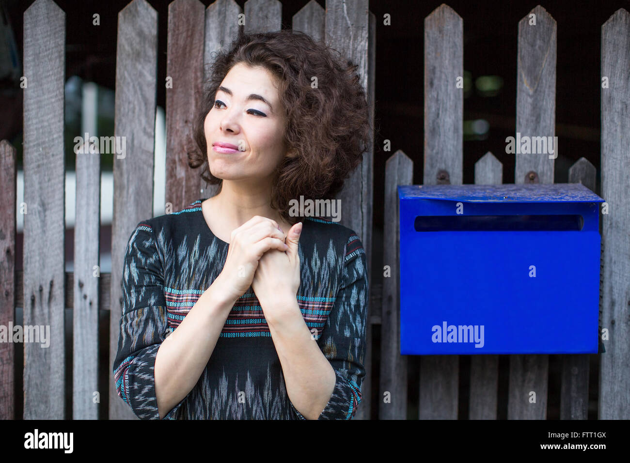 Schöne junge asiatische Frau steht am Zaun mit einem Postfach. Stockfoto