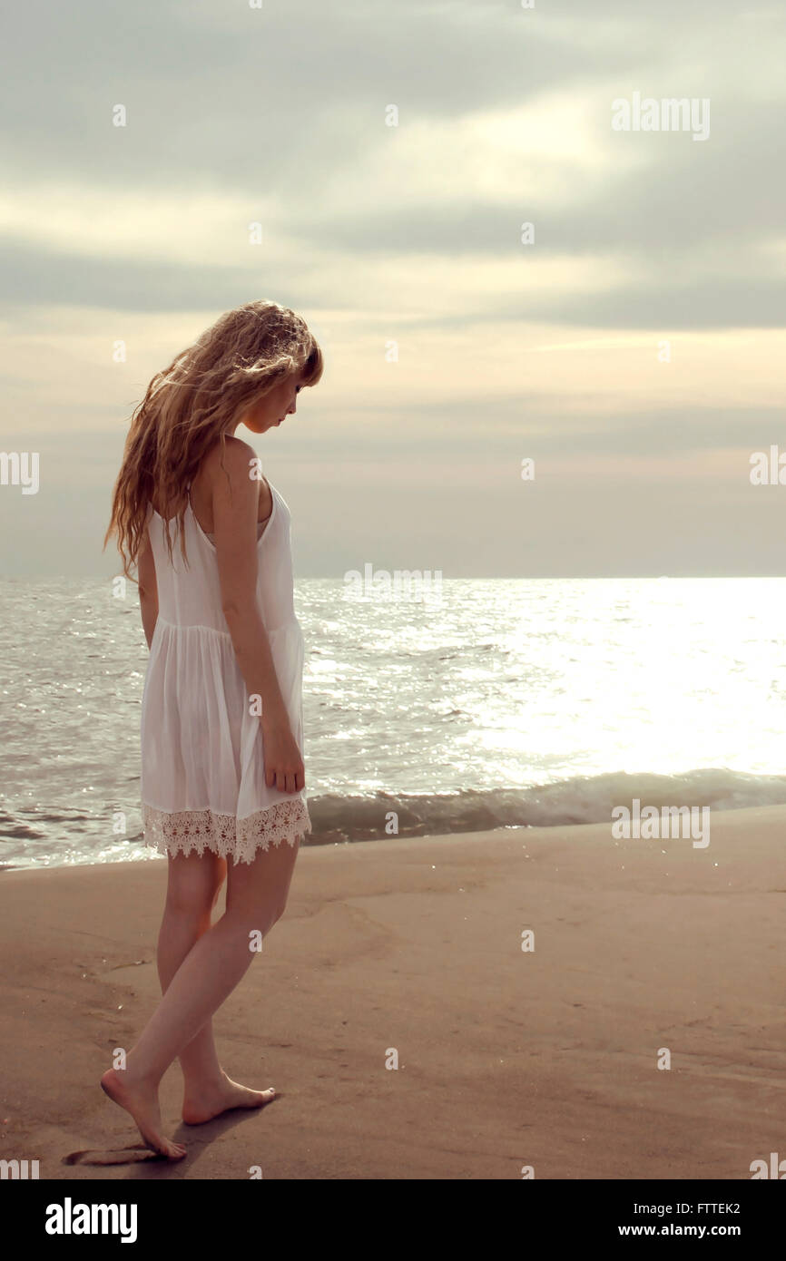 Blonde Frau zu Fuß am Strand mit Blick nach unten Stockfoto