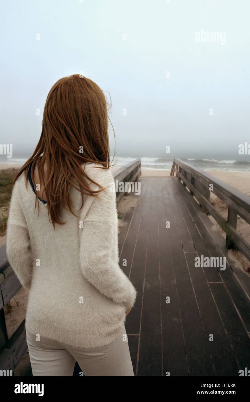 Frau zu Fuß auf Holzsteg am Strand Stockfoto