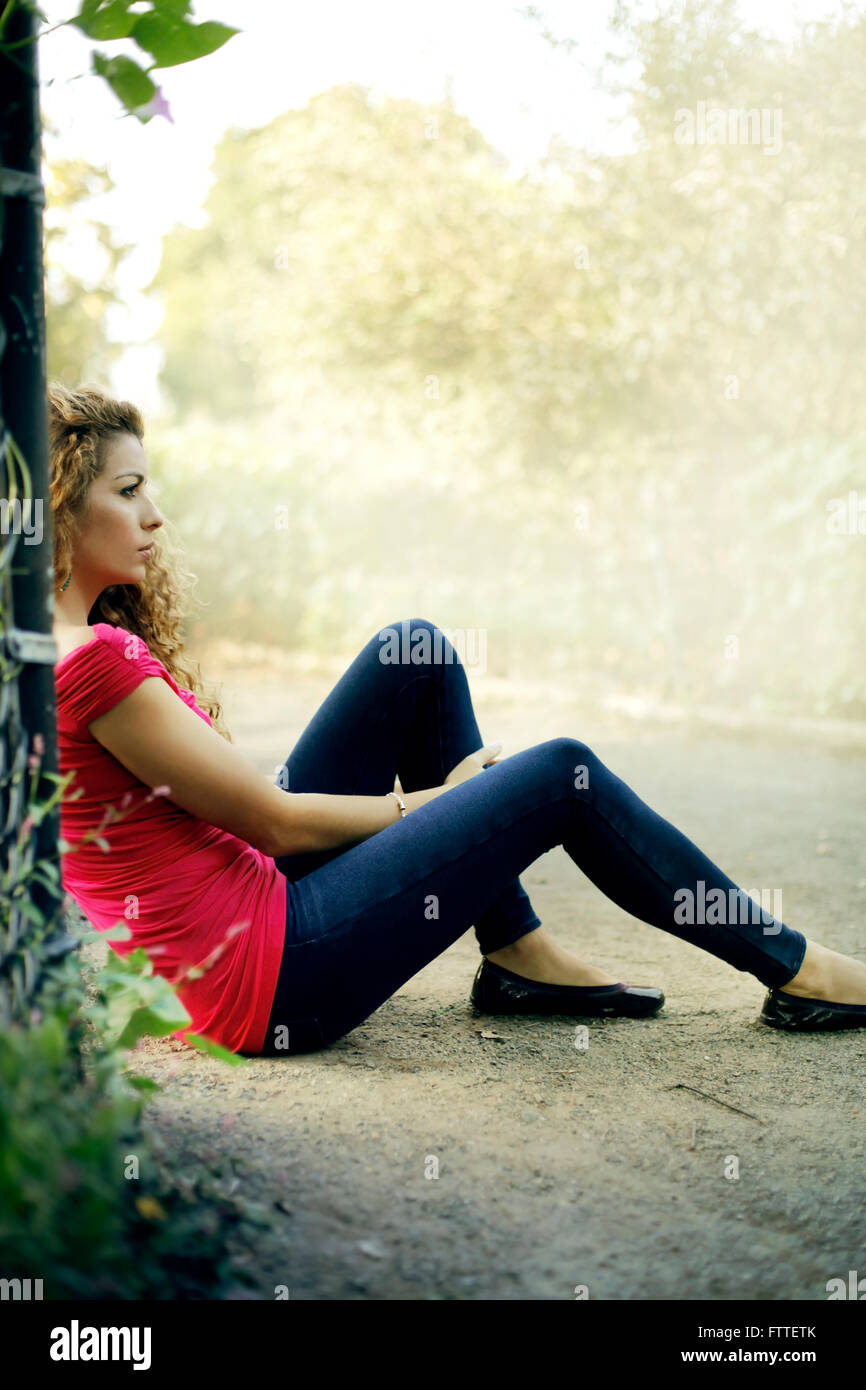 Lässige junge Frau sitzt im park Stockfoto