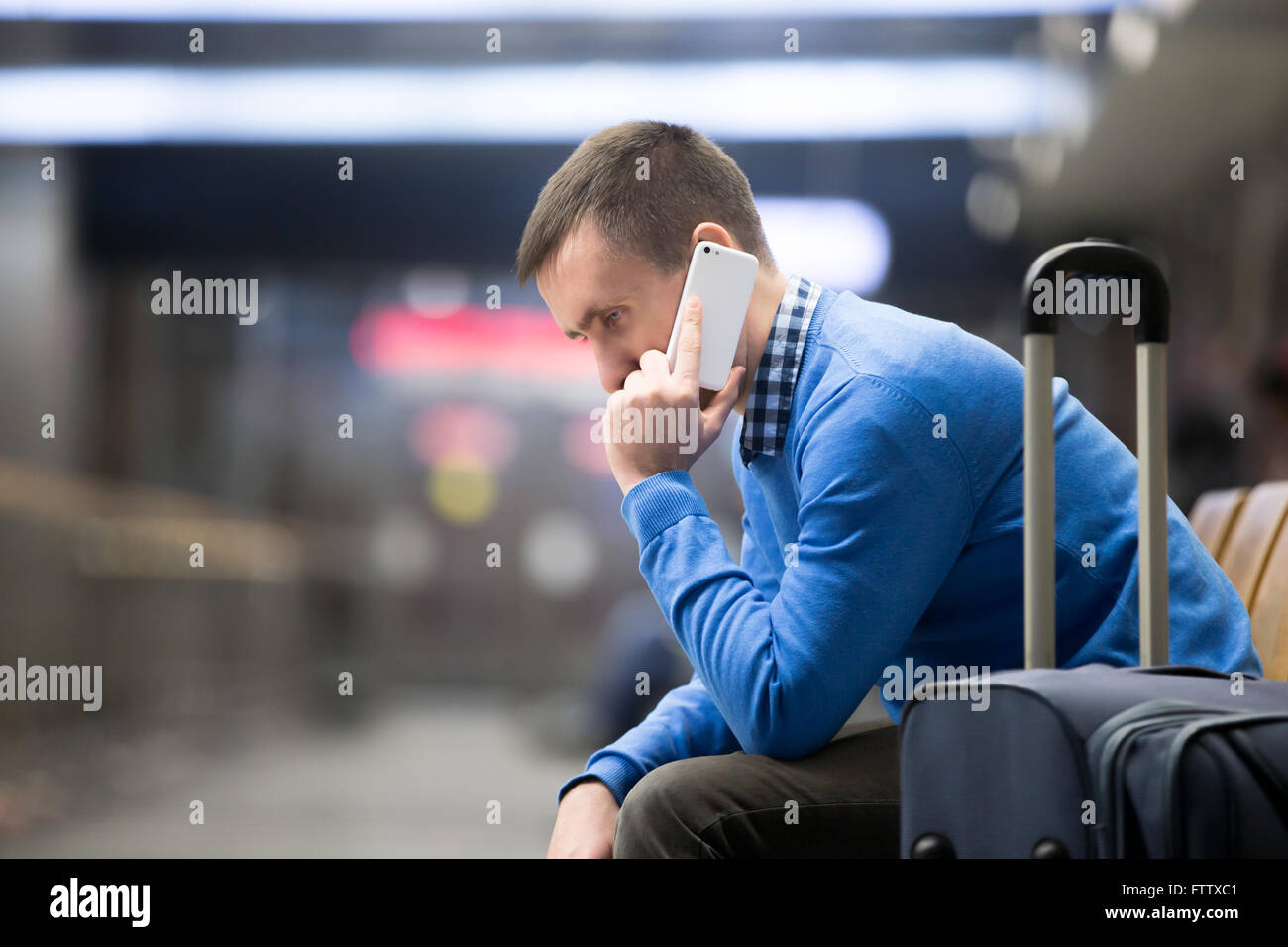 Porträt des jungen schöner Kerl casual-Style Kleidung warten auf Transport in modernen Bahnhof. Reisenden machen Anruf Stockfoto