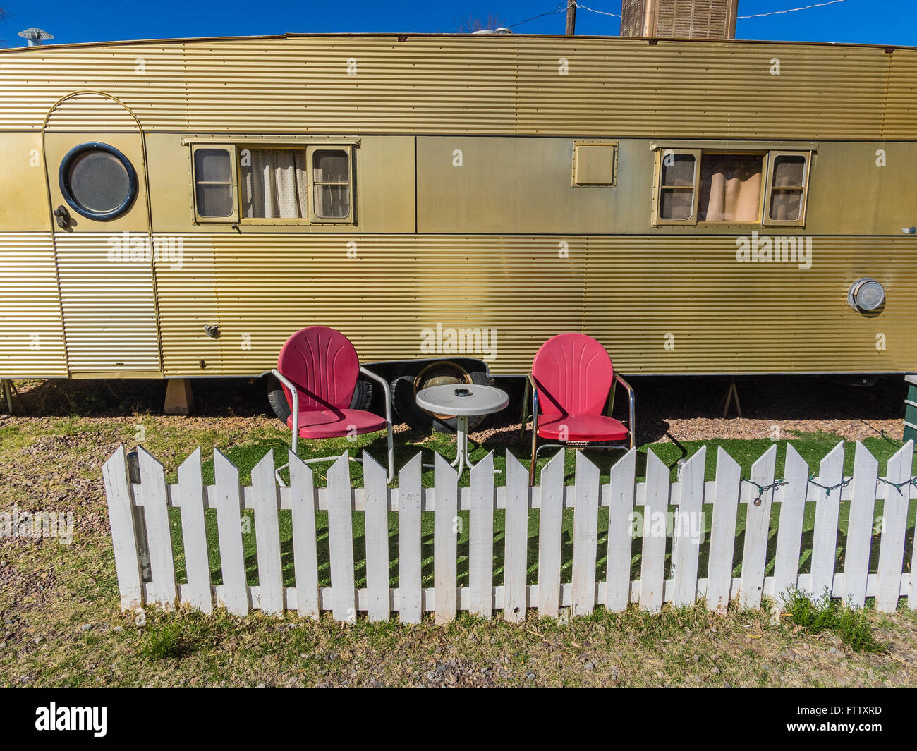 Zwei rote alten Stil Metall Rasen, die Stühle draußen ein Airfloat Flaggschiff Marke klassische Aluminium Antik gold farbigen Wohnwagen sitzen. Stockfoto