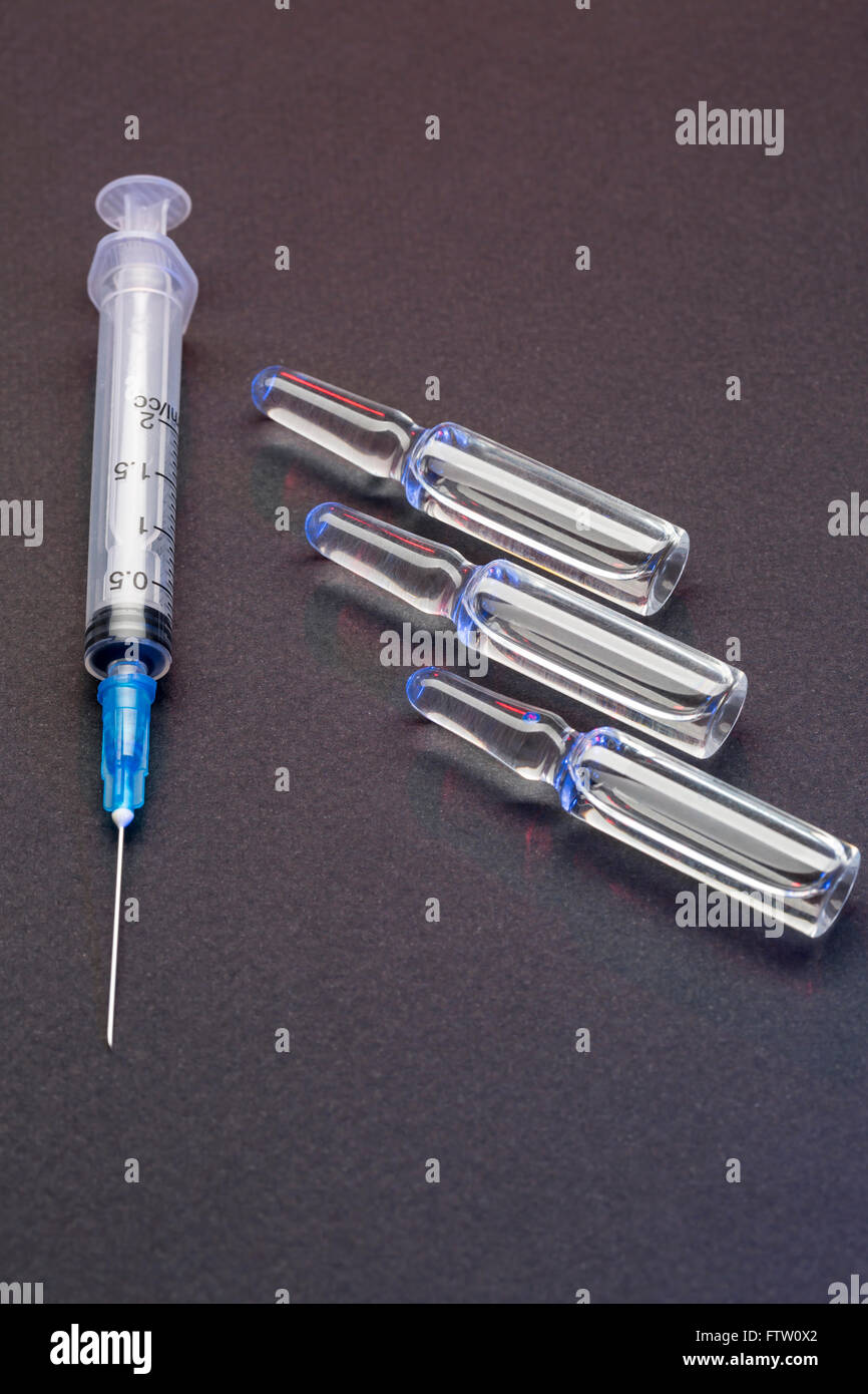 Einweg-Spritze für die Injektion und Glas Ampullen auf schwarzem Hintergrund Stockfoto