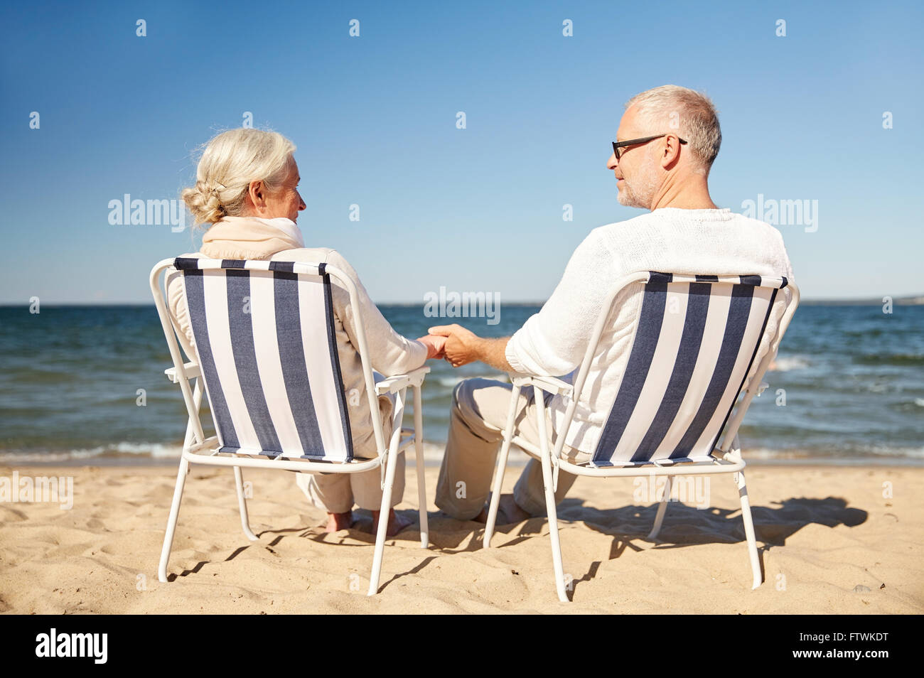 gerne älteres Paar in den Stühlen am Sommerstrand Stockfoto